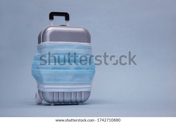 Time\
to travel. The concept of safe rest during a pandemic Covid-19\
Coronavirus. Suitcase for travel with a medical\
mask