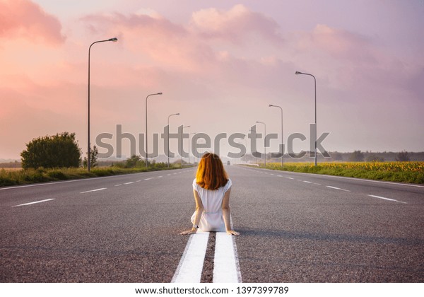 time to travel. girl sits on the dividing strip on\
the road\

