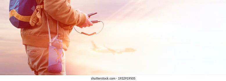 Time to Travel. Tourist holds a power bank in his hands and charges a smartphone while traveling. A man on the background of the sea and the plane on vacation - Shutterstock ID 1932919505