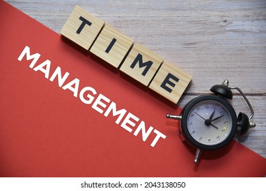 TIME Wording On Wooden Blocks And MANAGEMENT Text On Red Background With Analog Alarm Clock. Business Concept.