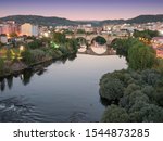 Time-blended image of the Roman bridge over the Miño River at sunset, as seen from the Millenium bridge, Ourense, Galicia, Spain
