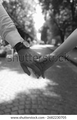 A timeless close-up of two hands clasped, showing the intimate connection between two people, rendered in classic black and white.