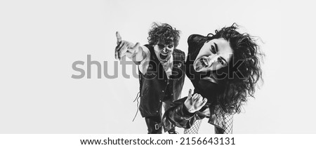 Timeless rock-and-roll. Black and white portrait of rock music fans, young boy and girl wearing black leather outfits moving on white studio background. Concept of style, art, fashion and youth, ad