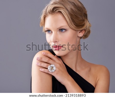 Timeless sophistication and chic. A gorgeous young woman in an evening gown while isolated on a grey background.