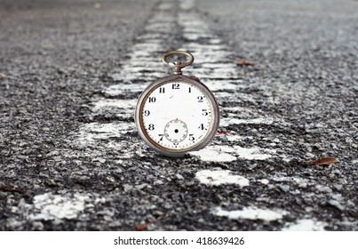 A Timeless Vintage Watch Resting On A Dividing Line In A Deserted Road Leading Into The Horizon For The Concept Of Crossing The Deadline.