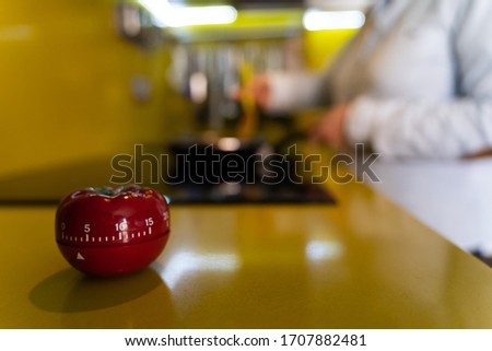 Timer to count the time on the yellow surface of a kitchen with a pan put of focus on the background