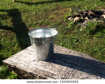 tin bucket on wooden bench, old country house, long shadow