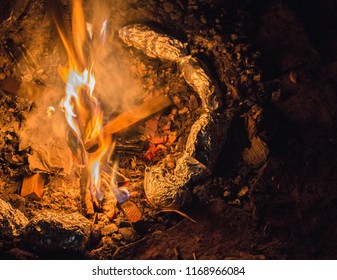 Tin Foil Wrapped Potatoes Cooking By The Side Of Bonfire During Camping. Long Exposure Shot Of Fire