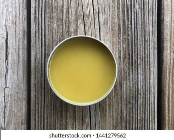 A tin of salve sits on a rough piece of wood - Shutterstock ID 1441279562
