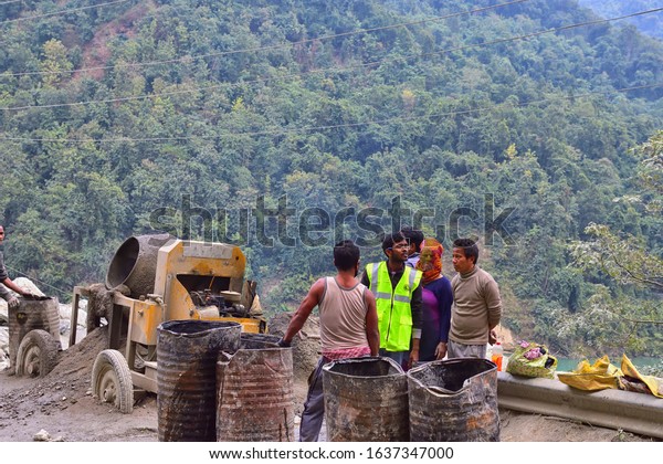 Tinchuley, Darjeeling, West Bengal, India-\
December 25, 2019: Men working at the construction road in inhuman\
conditions . man at work on a mountain\
road.