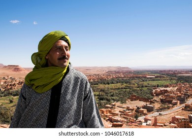 Tinghir, Morocco- 03-01-2018: Berber Man Standing In Front Of His Village Tinghir Morocco. Scenic View On The Valley Of Tinghir. Travel Destination. Local Guide Showing His City. 