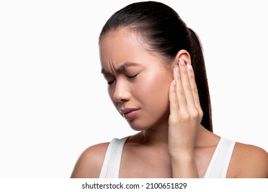 Tinnitus, otitis, otalgia concept. Sie view of sick young asian female having ear pain, touching her painful head, panorama with copy space, white studio background, closeup photo