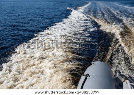 tinny dinghy boat on the water making a wake behind a boat making waves on a river in a national park in australia. beach in summer