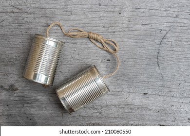 tins telephone with rope connecting on wooden background