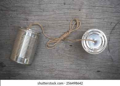 tins telephone with rope connecting on wooden background