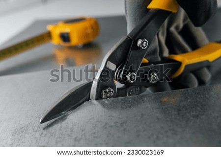 tinsmith cutting metal sheet with tin snips