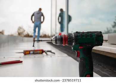 Tinsmith worker using cordless drill screws,  scissors to cut the metal sheet and sealant gun to install new metal sheet roof