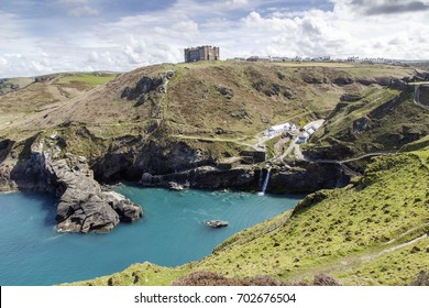 Tintagel, Cornwall, UK: April, 2016: A View Of The Main Entrance To Tintagel Castle In The Valley And Hotel Camelot On The Cliff. There Is A Beach Cafe, Visitors Centre At The Entrance.