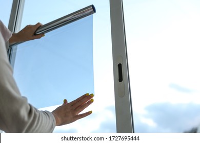 tinted glass in the house. window dimming by dark film. hands apply tint film to the window. tint film on sky background. sky view through tinted glass