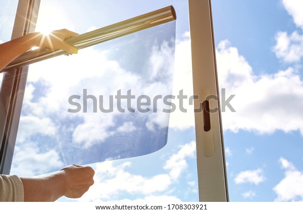 tinted glass in the house. window dimming by\
dark film. hands apply tint film to the window. tint film on sky\
background. sky view through tinted\
glass