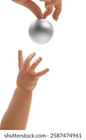 Tiny baby's hand reaching for shiny silver ball held above by parent against white studio background. Concept of curiosity, connection, discovery, early learning.
