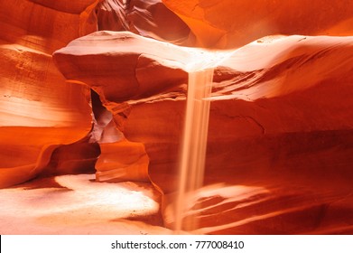 A tiny beam of sand is flowing off the rocks  in the interior of the narrow walls of the winding Antelope Canyon in Navajo Tribal Park, near  Page Arizona. 
