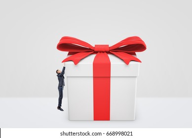 A tiny businessman trying to get into a huge white and red gift box. Profitable business. Best deal. How to get rich.