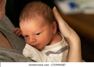 Tiny caucasian newborn baby boy resting in mothers arms after breastfeeding session. Baby with yellow skin because of baby jaundice, typical condition for first days of newborns life.