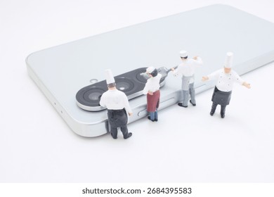 Tiny chef figurines gather around a sleek smartphone