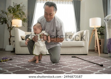 A tiny child practice walking on the floor in the living room with grandfather