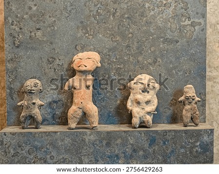 Tiny clay figures stand on a weathered stone ledge. Each figure shows distinct postures and expressions. They appear ancient, handcrafted with care and intention. Their surfaces are worn