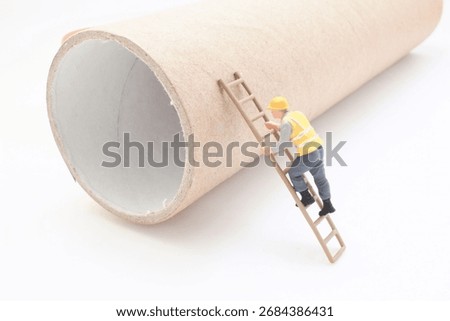A tiny construction worker figurine with a yellow vest and helmet