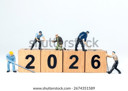 Tiny construction worker figurines working on wooden blocks showing the number 2026, symbolizing progress and the future.