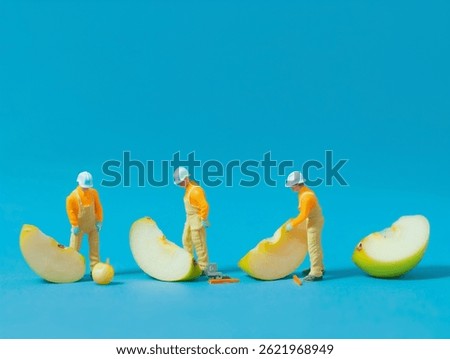 Tiny construction workers building a slice apple on a blue background.
