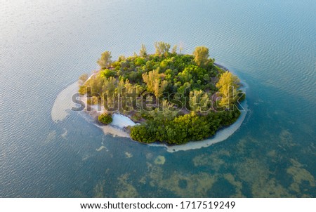 Tiny desert island in ocean. Small green uninhabited island. Blue sea water. Beautiful wildlife. Wild tropical nature Summer vacations. 