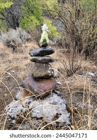 A tiny dragon perched high upon a tower of stones in the woods