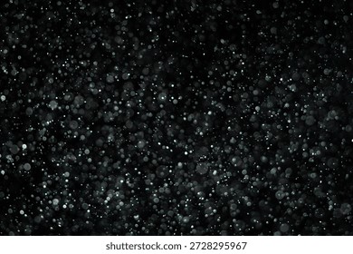 Tiny dust particles fly randomly in the smoky air, an empty template of space for objects. Many glittering particles of powder fall onto an empty black contrasting background in the rays of light.