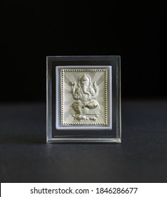 Tiny Embossed Silver Ganesha Frame On Black Background. Hindu Idol Photo Made With Precious Metal As Gift Items.