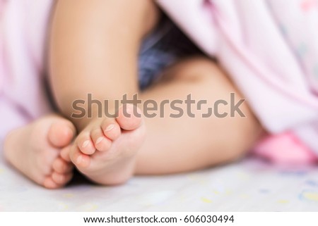 tiny feet of cute Asian baby sleeping on bed at home