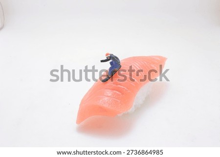 Tiny figurine glides along smooth pink seafood surface