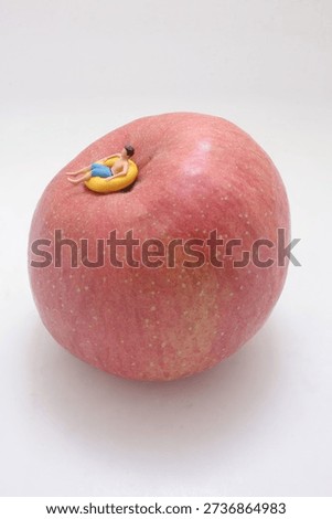 Tiny figurine lies floating ring on curved fruit