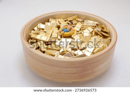 Tiny figurine lounges in float ring on stacked gold bars