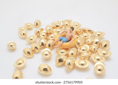 Tiny figurine rests in inflatable ring atop shiny gold pieces