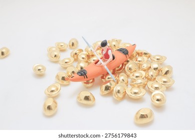 Tiny figurine rows kayak surrounded by reflective gold pieces