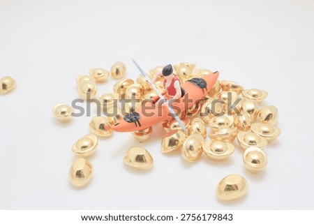 Tiny figurine rows kayak surrounded by reflective gold pieces