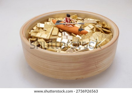 Tiny figurine rows orange kayak over stacked gold bars