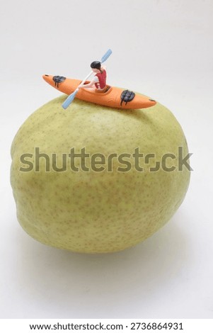 Tiny figurine rows small kayak across curved fruit