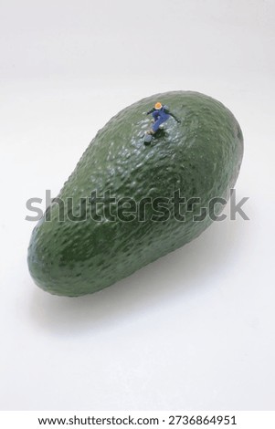 Tiny figurine rows small kayak along curved green fruit