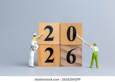 Tiny figurine workers painting and assembling wooden blocks to form the number 2026, symbolizing preparation, planning, and new beginnings.