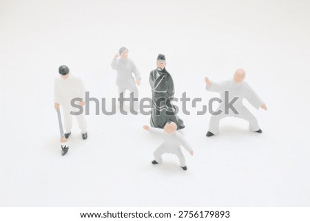 Tiny figurines demonstrate coordinated poses wearing traditional styled outfits